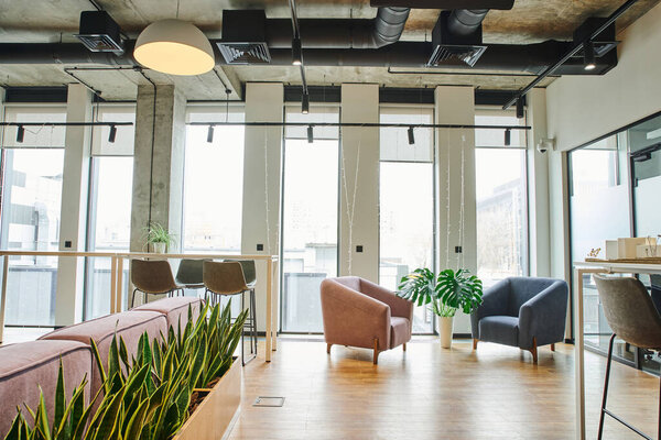 уютный зал ожидания с большими окнами, мягкими и удобными креслами, зелеными и натуральными растениями в современной коворкинговой среде, концепция организации рабочего пространства