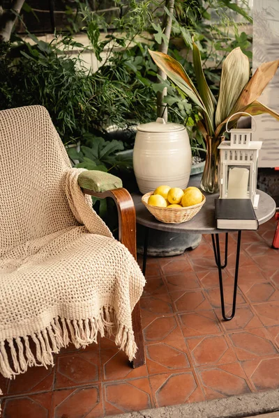 新鲜柠檬和书放在桌旁 靠近扶手椅和绿色植物 背景在室内花园 维生素C 酸食品 室内花园的水果 夏天的概念 — 图库照片