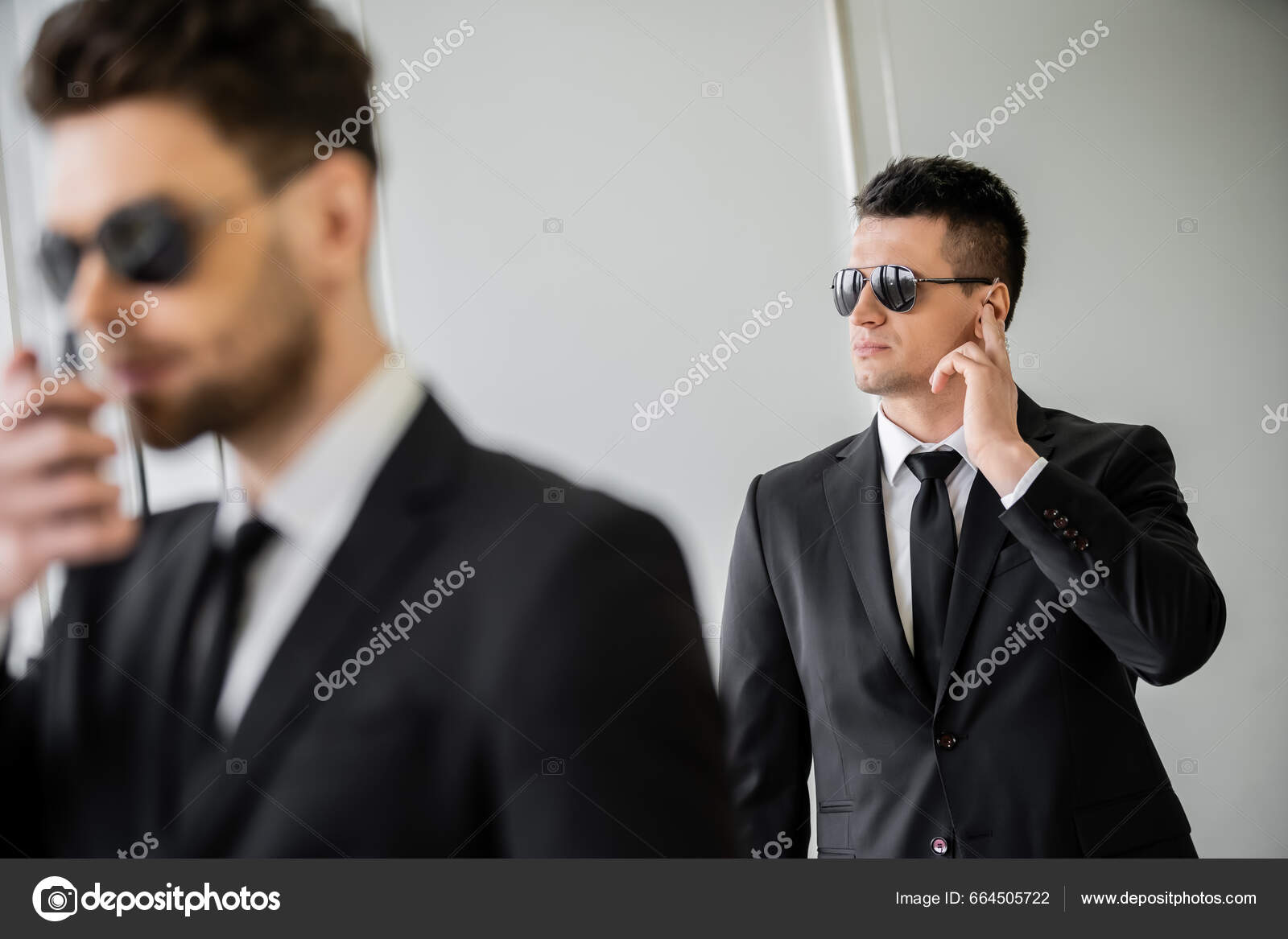Serious Bodyguard Standing with Sunglasses and Security Earpiece