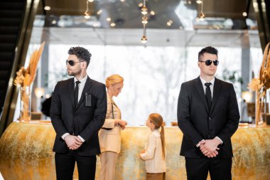 personal security, handsome bodyguards in suits and sunglasses protecting mother and child in hotel lobby, luxury lifestyle, woman and girl standing at reception desk clipart