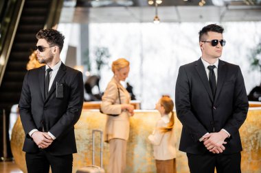 personal security, handsome bodyguards in suits and sunglasses protecting life of mother and child in hotel lobby, rich and luxury lifestyle, woman and girl standing at reception desk clipart