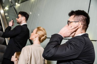 Özel güvenlik, müşterilerin güvenliğini korurken iletişim kuran profesyonel korumalar, zengin yaşam tarzı, sarışın ve başarılı kadın ve otelin yürüyen merdiveninde duran küçük çocuk.