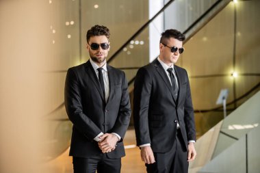 security management of luxury hotel, two handsome men in formal wear and sunglasses, bodyguards on duty, safety measures, vigilance, suits and ties, private security, strong guards  clipart