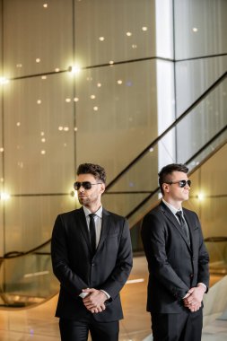 security management of luxury hotel, handsome men in formal wear and sunglasses, bodyguards on duty, safety measures, vigilance, suits and ties, private security, strong guards  clipart