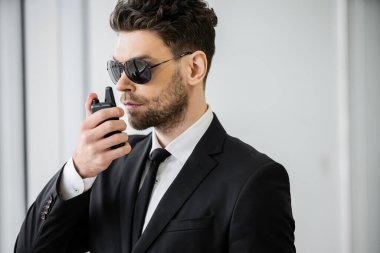 surveillance, handsome bodyguard communicating through walkie talkie, man in sunglasses and black suit with tie, hotel safety, security management, uniformed guard on duty, professional headshots  clipart