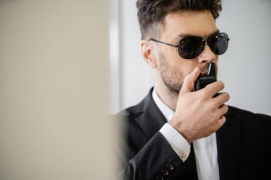surveillance, bodyguard communicating through walkie talkie, man in sunglasses and suit with tie, hotel safety, security management, uniformed guard on duty, professional headshots  clipart