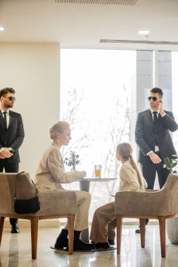 security service, private safety concept, bodyguards standing near female clients, preteen girl and blonde mother spending time together in cafe, personal safety and protection  clipart