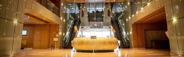modern hotel interior with round reception desk and sophisticated lobby design, escalators, moving staircase, luxurious ambience, spacious and comfort, classy and chic, banner  clipart
