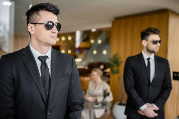 stock image private security , personal safety service, handsome bodyguards in formal wear and sunglasses protecting safety of female client on blurred background, mother and daughter in cafe 