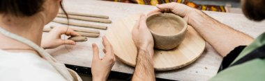 Cropped view of romantic couple molding clay while working in ceramic workshop, banner clipart