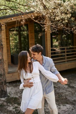 Mutluluk ve kahkaha, mutlu adam tatil evinin yakınında kadına sarılıyor, yaz aşkı ve romantizm.