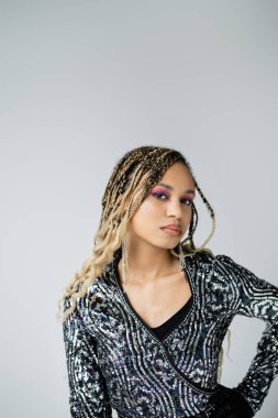 Gri arka planda poz veren cesur makyajlı güzel Afrikalı Amerikalı kadın kameraya bakıyor.