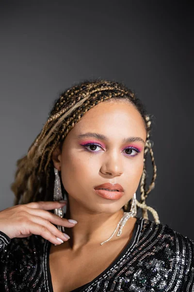 Lüks takılar takmış Afrikalı Amerikalı kadın portresi gri arka planda kameraya bakıyor, parti
