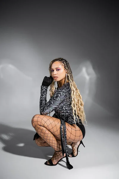 diversity, african american woman in gloves and fishnet tights, posing on grey background, style
