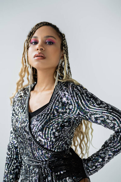party style, african american woman with bold makeup posing with hand on hip, grey background