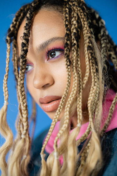 close up of beautiful dark skinned woman with dreadlocks on blue background, diversity, portrait
