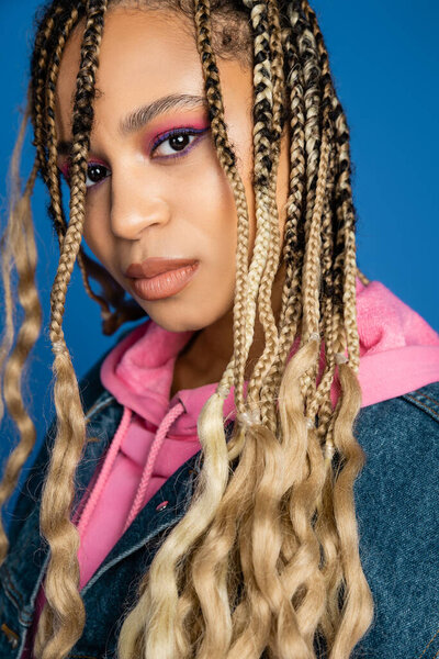 beautiful african american woman in pink hoodie and denim vest looking at camera, dark skinned