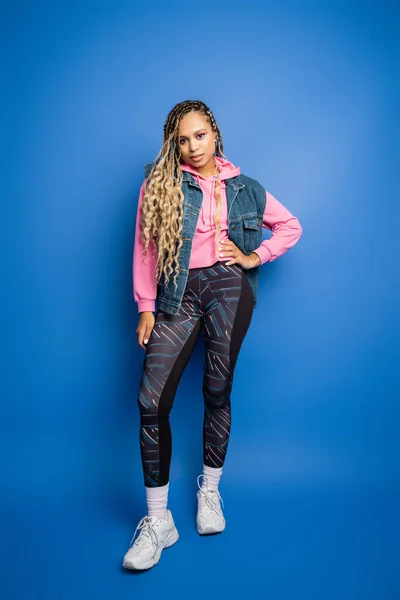 stock image full length of confident african american woman with dreadlocks posing with hand on hip in studio