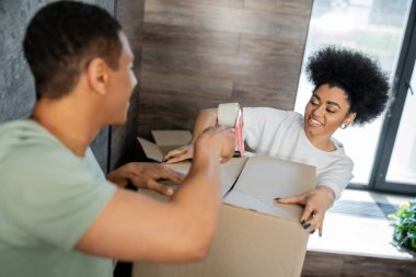 Pozitif Afro-Amerikan çift taşınma sırasında yapıştırıcı bant ile karton kutu paketleme