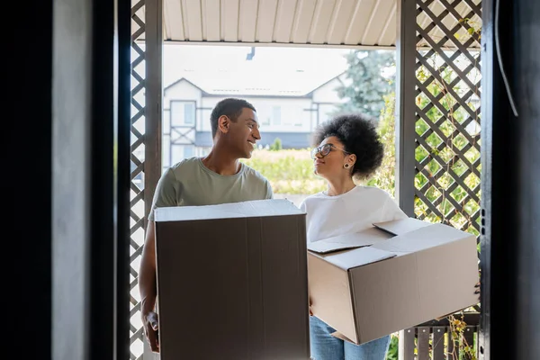 stock image smiling romantic african american couple holding carton boxes near door of new house