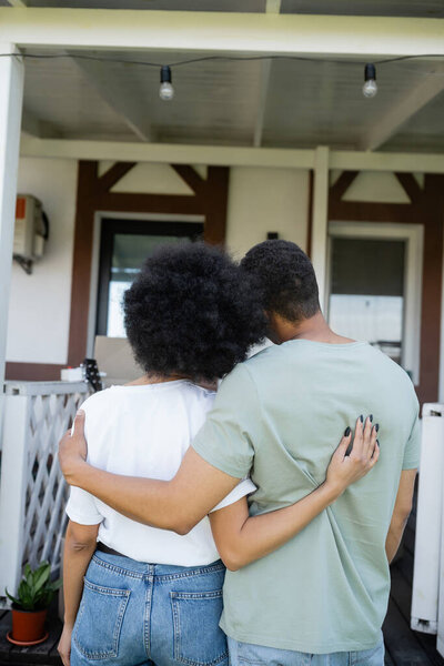 back view of african american couple embracing near new house outdoors