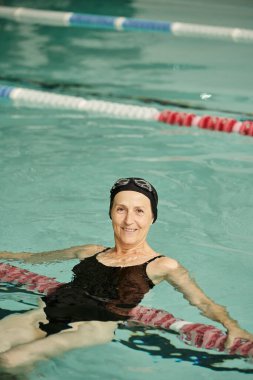 neşeli ve formda orta yaşlı kadın havuzda yüzüyor, yüzme şapkası ve gözlükleri, sağlıklı yaşam tarzı, spor