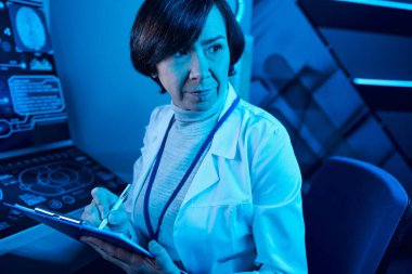 Futuristic Expertise: Senior Woman Scientist Records Data and Contemplates in Future Science Center clipart