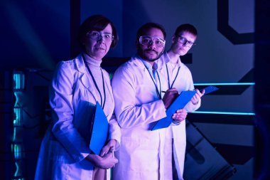 Futuristic Focus: Three Scientists Engage in Headshot Analysis Within Neon-Lit Science Center. clipart