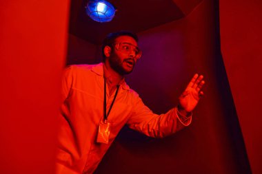 Kırmızı neon ışıkta kırmızı neon ışığı altında şok olmuş Hintli bilim adamı, bilinmeyen bir fenomen.