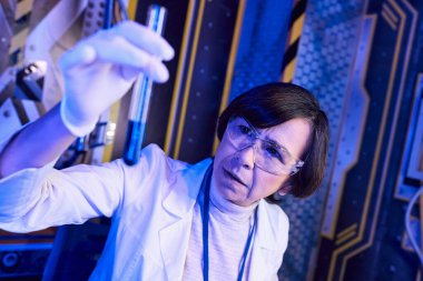 Dünya dışı yaşamı araştıran kadın bilim adamı, gelecekteki laboratuarda sıvı numunesiyle test tüpü tutuyor.