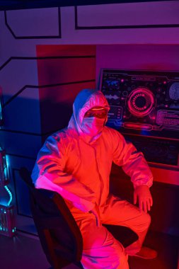 future-oriented indian scientist in hazmat suit sitting in experimental laboratory clipart