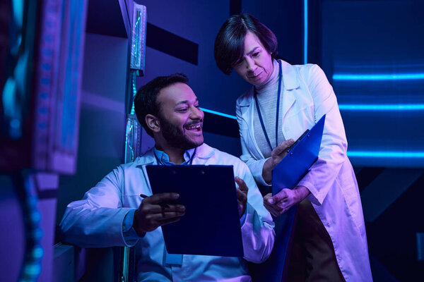 Индуистские ученые мужского и взрослого пола анализируют данные и делятся улыбками в научном центре неоновой литературы