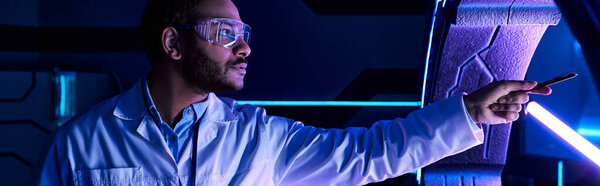 индийский ученый в очках, указывающих на экспериментальное оборудование в исследовательском центре, баннер