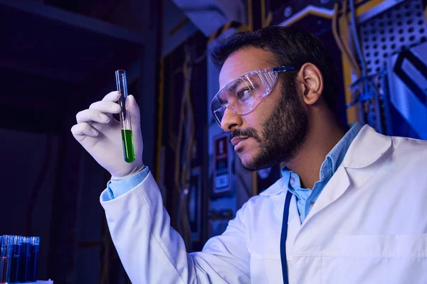 futuristic concept, indian scientist in goggles holding test tube with liquid sample in lab, banner