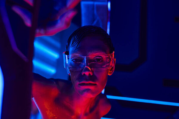 scientific breakthrough, alien in goggles looking at camera near high-tech device in science center