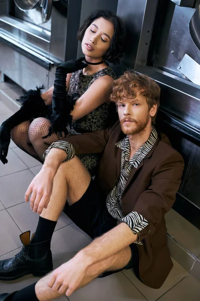 stock image trendy young asian man looking at camera near asian girlfriend in public laundry