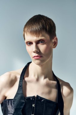 Siyah korseli çift cinsiyetli model gri, lgbt, acayip moda, tarz kameraya bakıyor.
