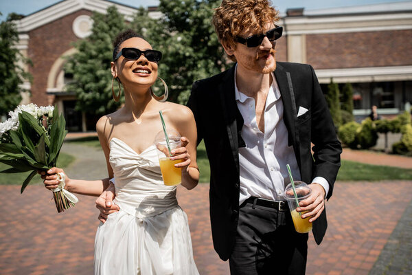 interracial couple, sunglasses, wedding attire, orange juice, flowers, happiness, outdoor wedding
