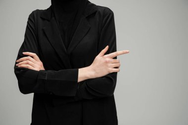 Siyah ceketli Müslüman iş kadınının gri kollarıyla poz verişi, kendine güven.