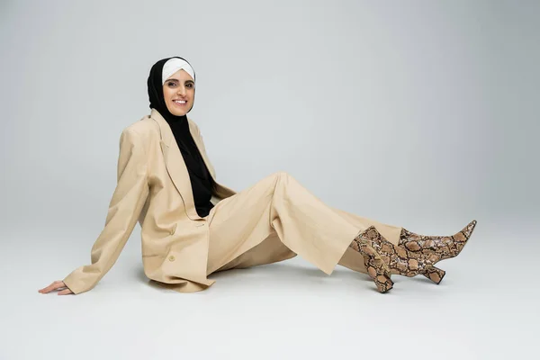 身穿头巾和商务休闲装的快乐的穆斯林妇女坐在那里 看着灰色的相机 — 图库照片