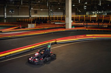 Hızlı sürüş, go-kart 'lı Afro-Amerikan adam, kapalı alanda karting pistinin içinde yarışıyor.