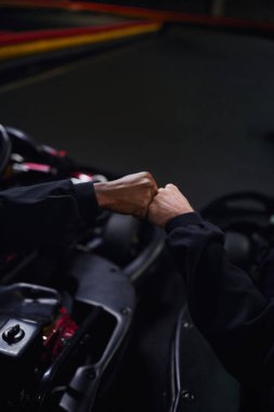 Çeşitli go kart sürücülerinin karting yapmak için spor arabalara yumruk atması ve oturması.