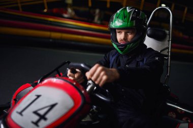 man in helmet and sportswear driving go kart on indoor circuit, adrenaline and motorsport concept clipart