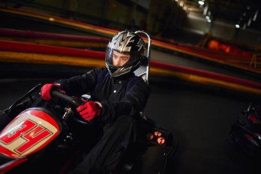 focused driver in helmet racing in go kart car on indoor circuit, speed drive and motorsport concept clipart