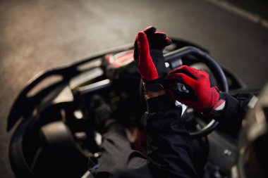 Kırmızı yarış eldivenleri giyen go kart sürücüsü yarışma konseptine hazırlanıyor.