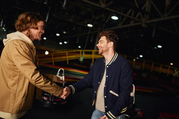 stock image happy man in glasses shaking hands with friend inside of karting racing track, competition