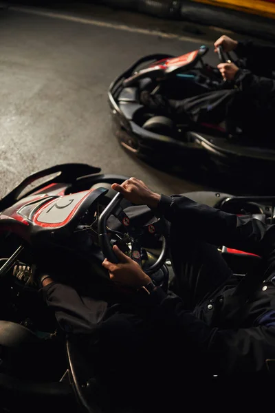 top view of two diverse go kart racers driving on indoor circuit, speed racing and motorsport