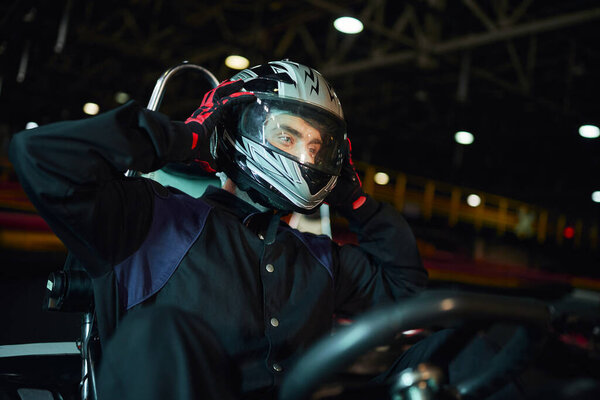 go kart driver taking off helmet after driving on circuit, speed drive and motorsport concept