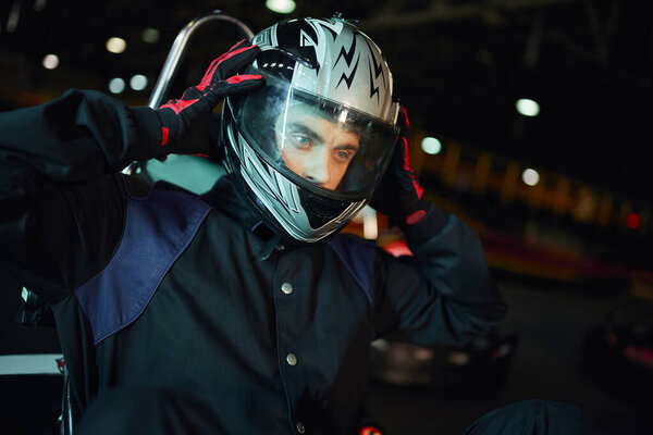 go kart driver taking off helmet after racing on circuit, speed drive and motorsport concept