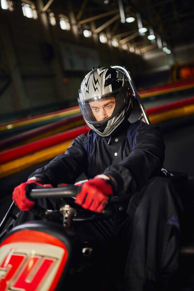 концентрированный гонщик в шлеме вождения go kart car на крытой трассе, концепция автоспортивных соревнований